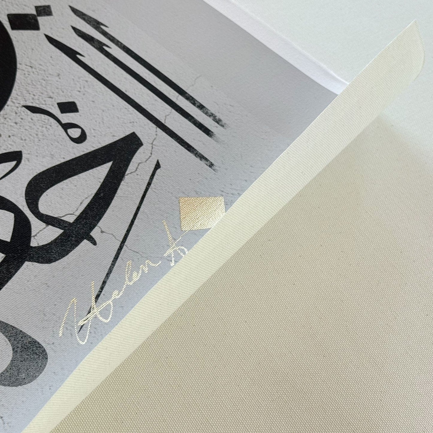 Close-up of a piece of art print with Arabic calligraphy on a textured canvas.